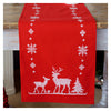 Red table runner with white reindeer and snowflake pattern on a wooden surface.