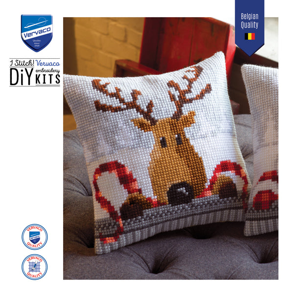 Embroidered pillow with reindeer design on a couch, featuring Vervaco branding.