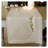 Embroidered table runner on a wooden table with candles and decorative balls.